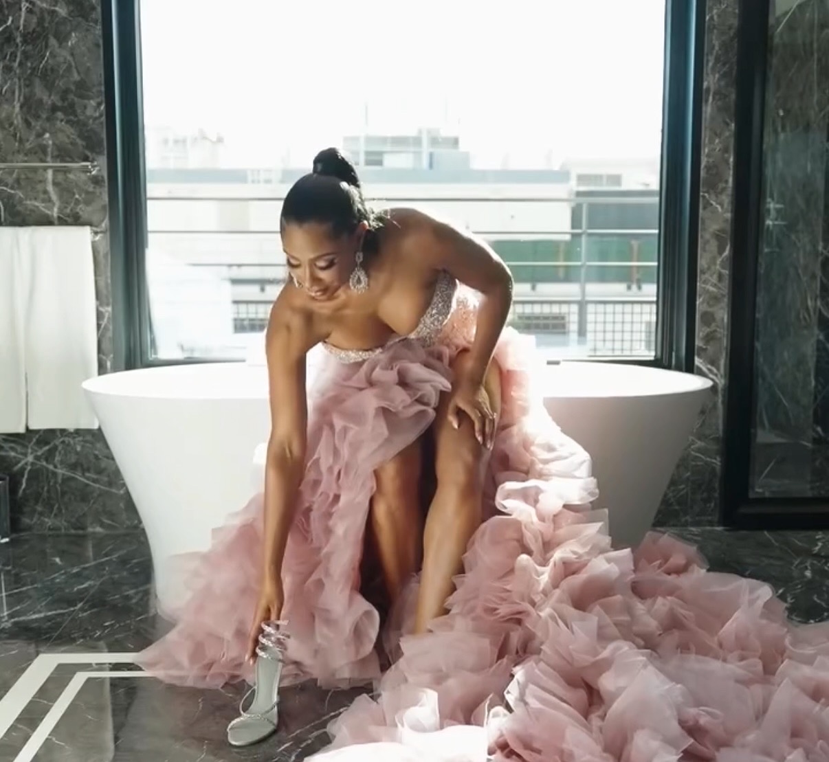 Jennifer Gold in a dramatic gown seated beside a freestanding bath.
